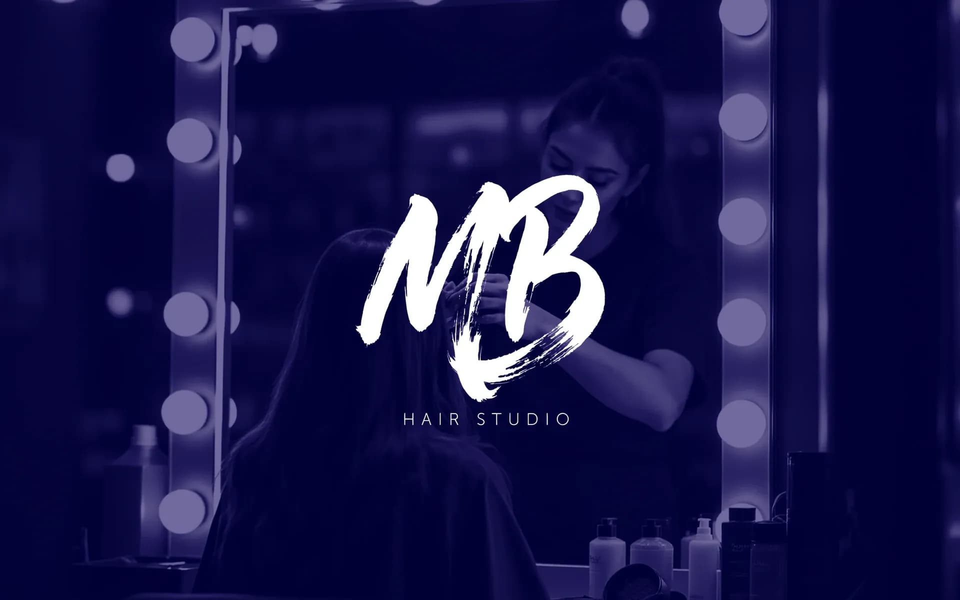 MB Hair Studio — logo na fotce kadeřnice při práci u zrcadla